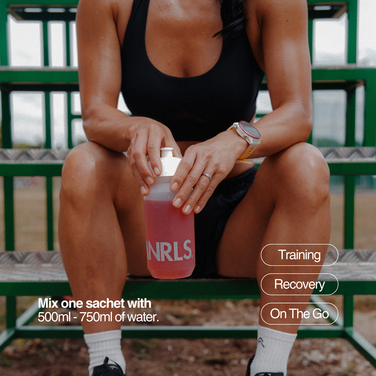 Athlete holding MNRLS Berry Cherry electrolyte drink bottle after mixing one sachet with water